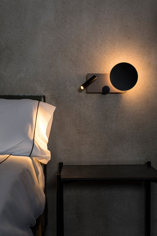 Vista ambiente de aplique de pared KLEE en gris texturizado lector derecho, modelo 20065 de FARO, luminaria interior LED COB regulable con diseño de Isaac Piñeiro, iluminación moderna para espacios hogareños.