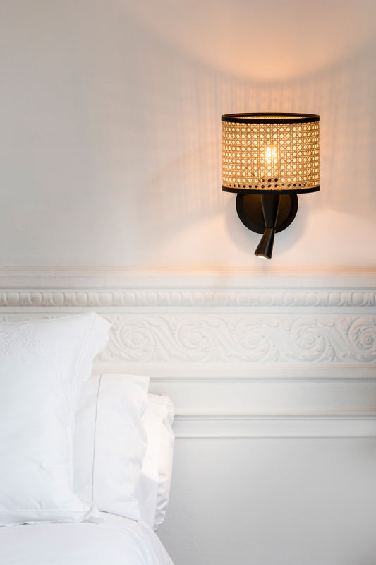 Aplique de pared MAMBO de FARO (64309-47) en negro mate con ratán y lector integrado, luminaria superficial para interiores de habitaciones en entornos hospitality, iluminación ambiente cálida y moderna.