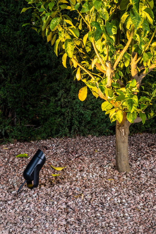 Visera antideslumbrante SLOT negra de aluminio para faro exterior modelo 70039 en ambiente de jardín moderno, accesorio iluminación proyector lámpara diseño contemporáneo