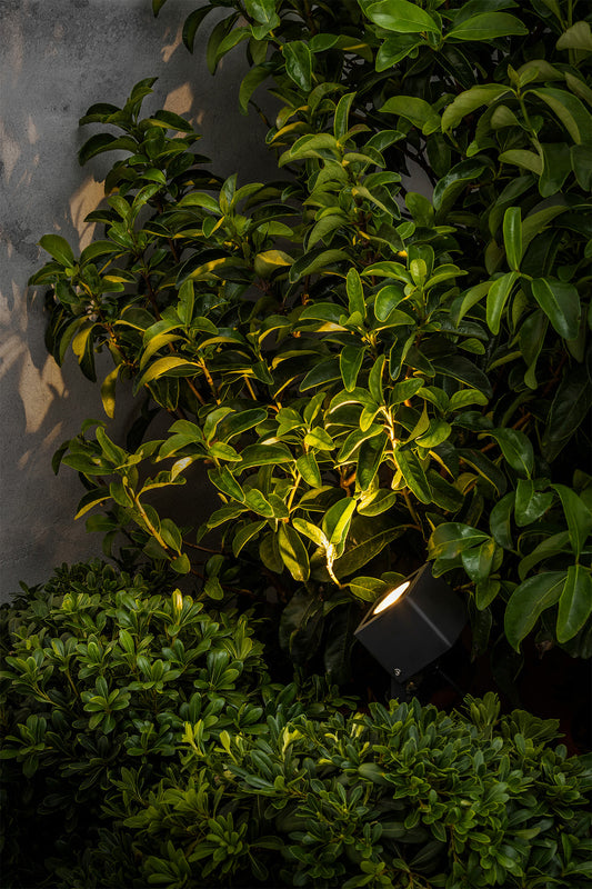 Proyector LED exterior SOBEK negro FARO 70151 en ambiente de jardín, luminaria de aluminio IP65 para iluminación exterior resistente al agua y polvo.