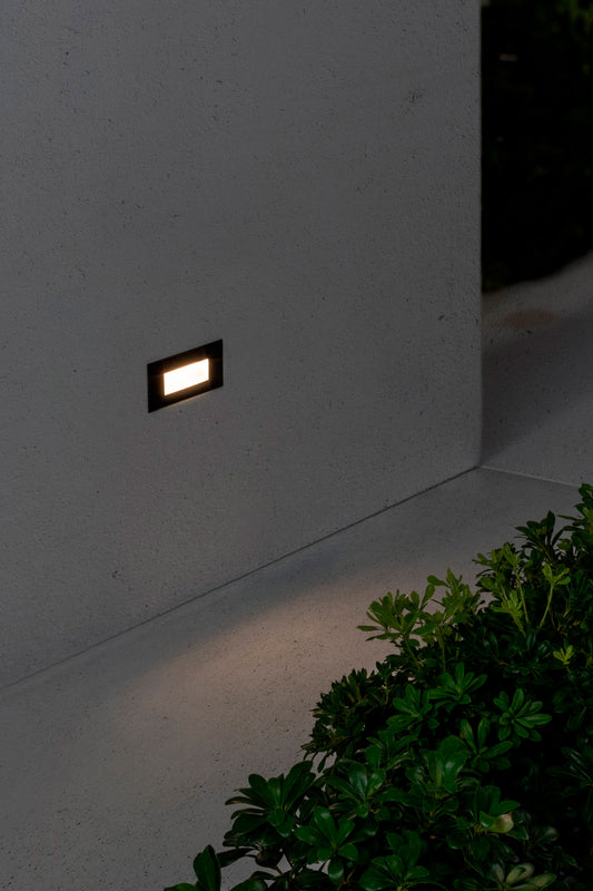 Luz empotrable LED exterior DART RCT negra 2700K FARO 70278 en ambiente de jardín, iluminación cálida policarbonato y cristal para señalización pared