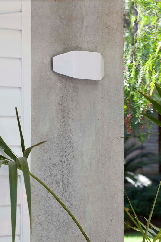 Lámpara de pared exterior Future Aplique Blanco FARO modelo 71516, diseño contemporáneo en blanco mate de policarbonato de la colección 1610, iluminando terraza y jardín en ambiente nocturno.