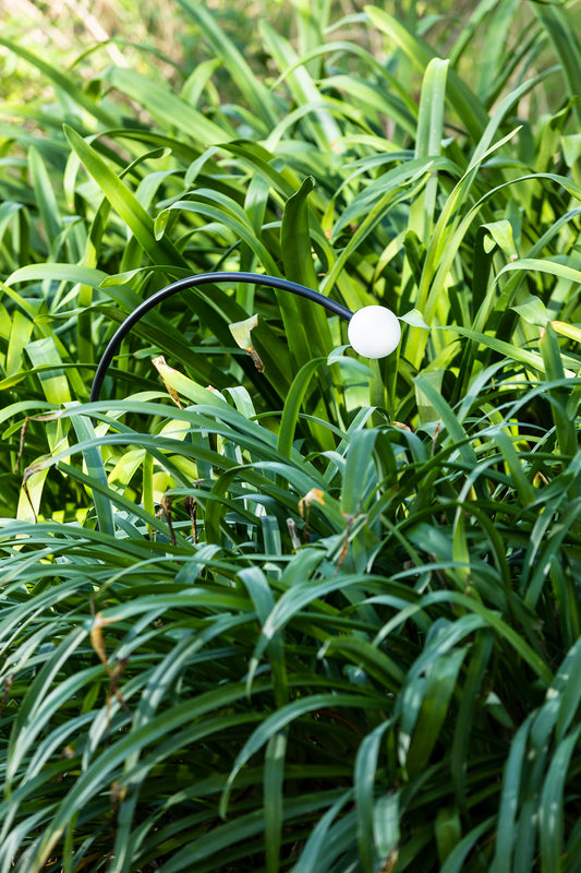 Luminaria estaca CUCA 650 negra 24V faro 75561 en ambiente de jardín exterior, diseño minimalista en acero inoxidable y cristal con protección IP65 para iluminación exterior.