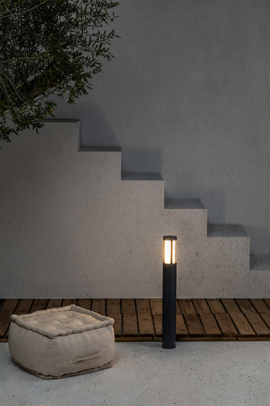 Baliza exterior LOGAR 650 en gris oscuro instalada en jardín, faro LED de aluminio y PMMA para iluminación suelo exterior con protección IP54.