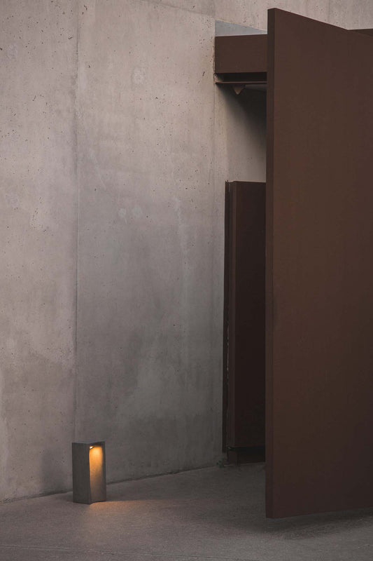 Baliza LED GROT 400 gris 2700K FARO 75631 en ambiente exterior de jardín, luminaria superficie en cemento iluminando zonas de paso con luz cálida, colección 7565