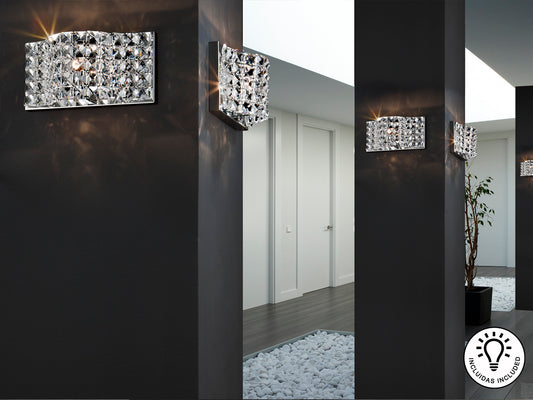 Aplique de pared Onda cromado para baño, dormitorio o salón, con diseño contemporáneo y detalles en cristal y metal. Iluminación LED G9 de 550 lúmenes, ideal para espacios glam y modernos. Producto Schuller.