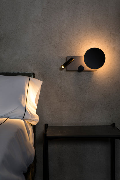 Vista ambiente de aplique de pared KLEE en gris texturizado lector derecho, modelo 20065 de FARO, luminaria interior LED COB regulable con diseño de Isaac Piñeiro, iluminación moderna para espacios hogareños.