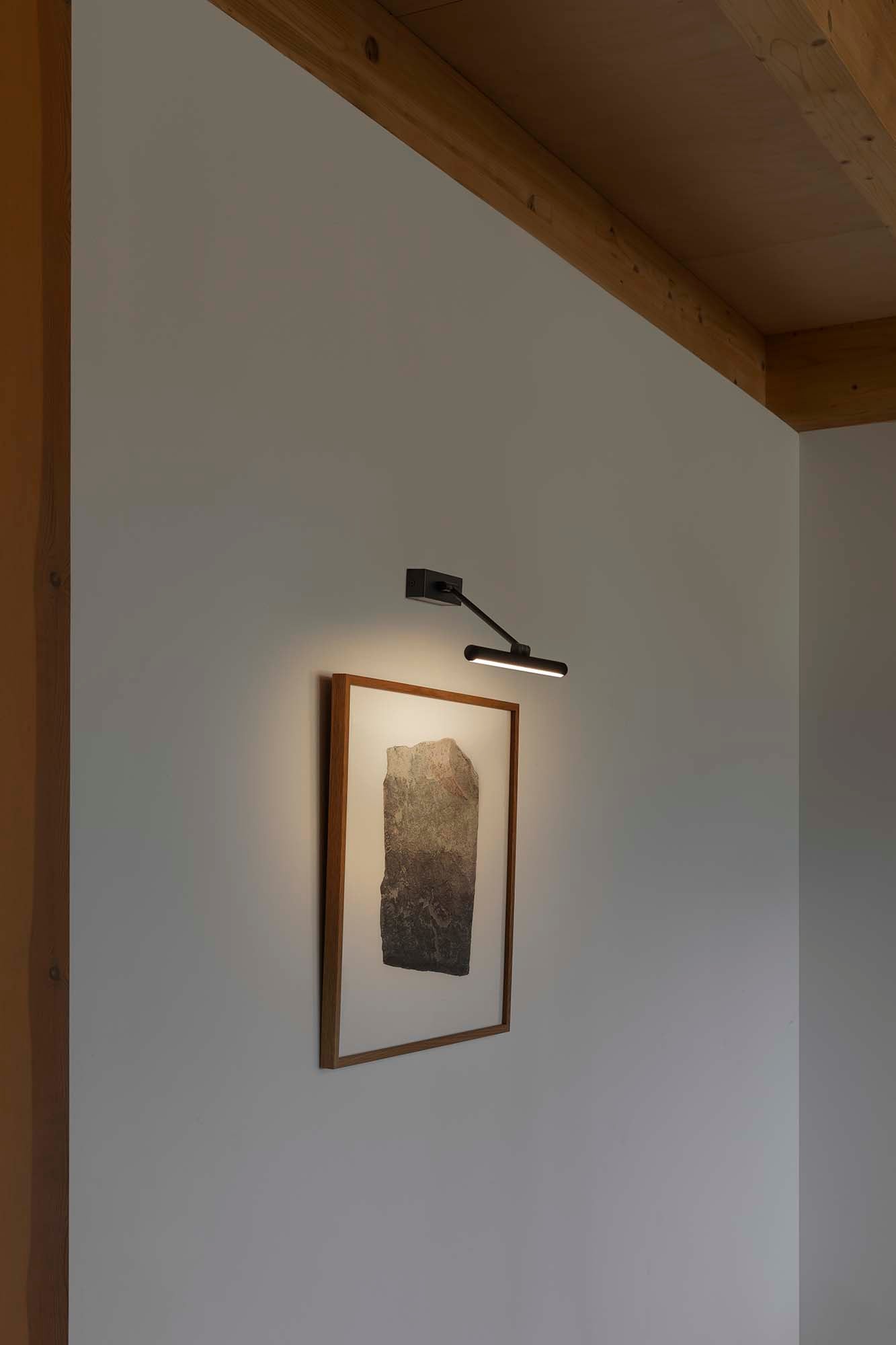 Lámpara iluminacuadros LED Magritte 300 Negro FARO 61086 en ambiente interior minimalista, luminaria de pared orientable negro mate con luz cálida 3000K para arte y decoración.