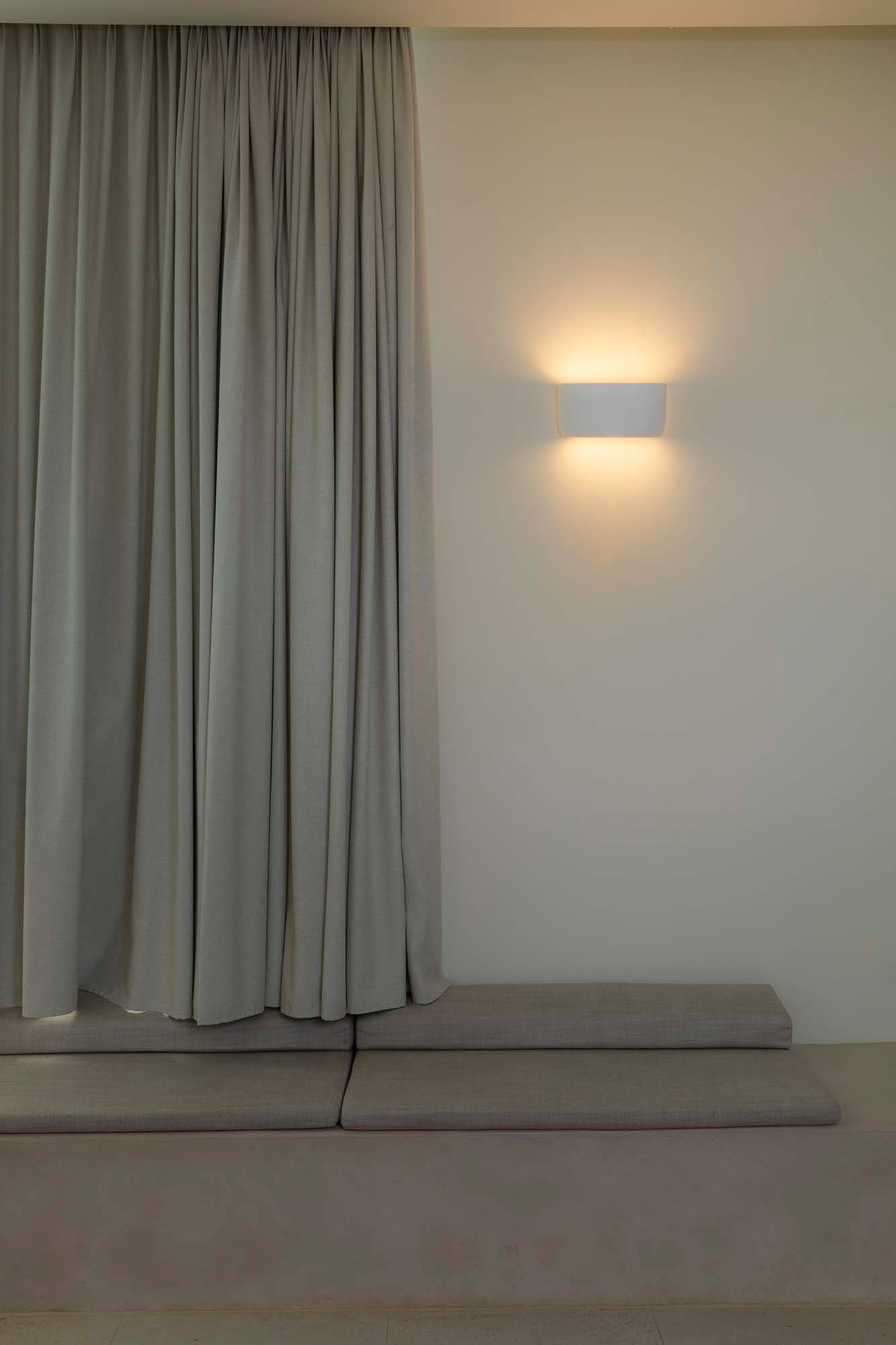 Imagen ambiente de aplique de pared KAPPU 300 blanco FARO 63430 en interior minimalista, luminaria de superficie en yeso con iluminación indirecta, colección 6362