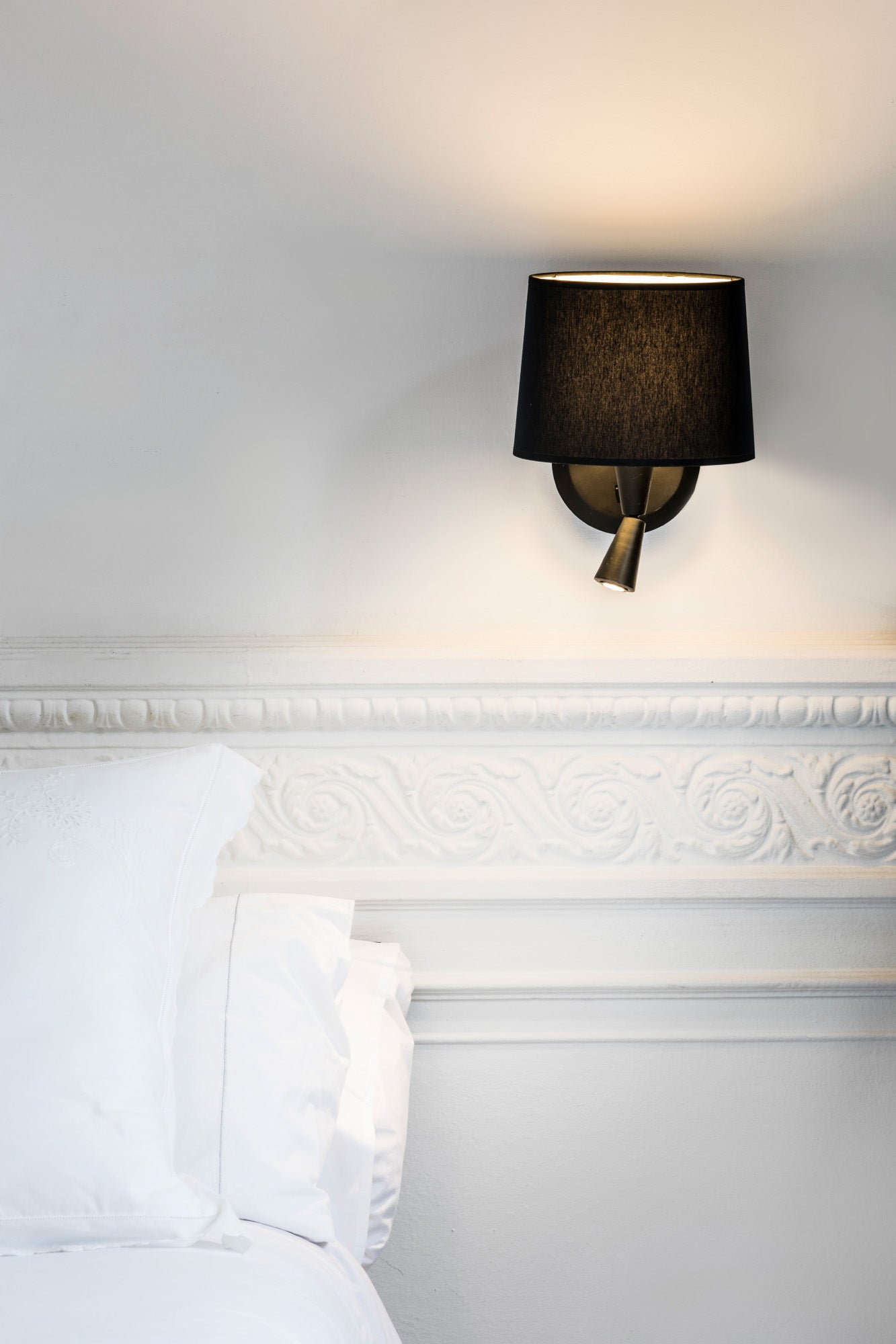 Aplique de pared CONGA con lector negro de FARO, modelo 64309-03, en ambiente interior de lectura; luminaria superficie en acero y textil para hospitality e iluminación interior