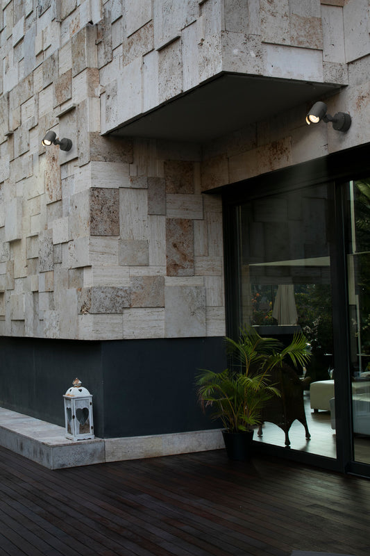 Proyector LED FOC 150 gris oscuro FARO 70156 en ambiente exterior, iluminando jardín y terraza con aluminio IP65 resistente al agua.