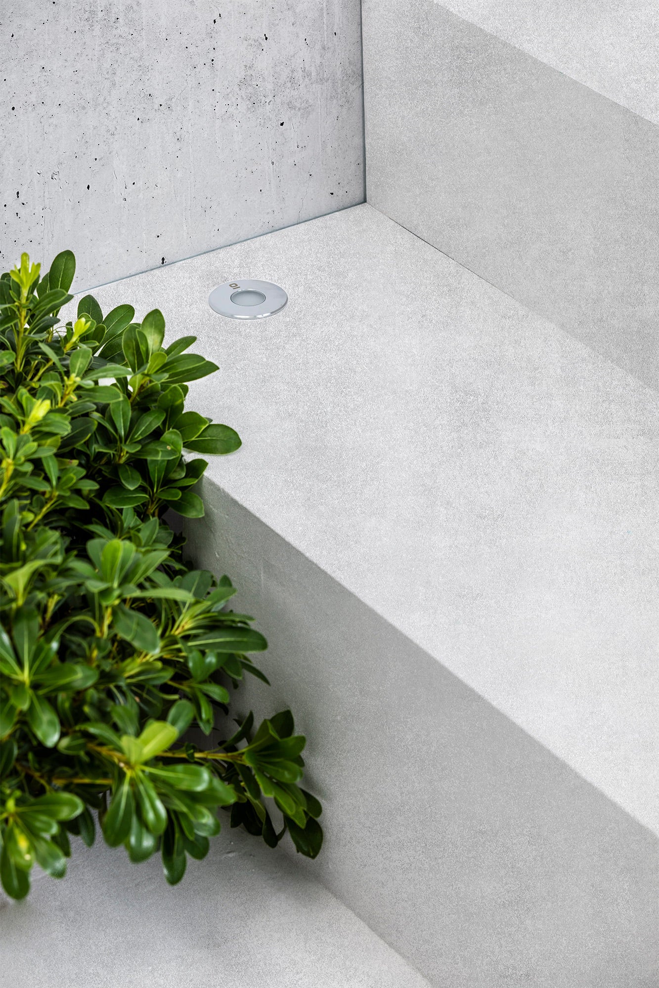 Luz empotrable CROSBY gris con luz cálida LED de FARO modelo 70459N en ambiente de jardín exterior, iluminación IP67 resistente