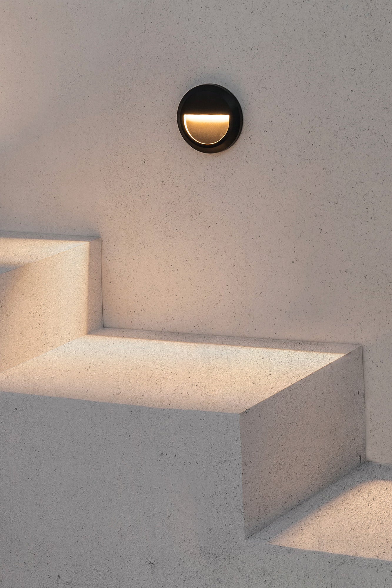 Lámpara de pared LED GRANT R de FARO en gris oscuro, modelo 70656, instalada en ambiente exterior de jardín con iluminación cálida 3000K, protección IP65, luminaria de superficie en ABS y policarbonato resistente.