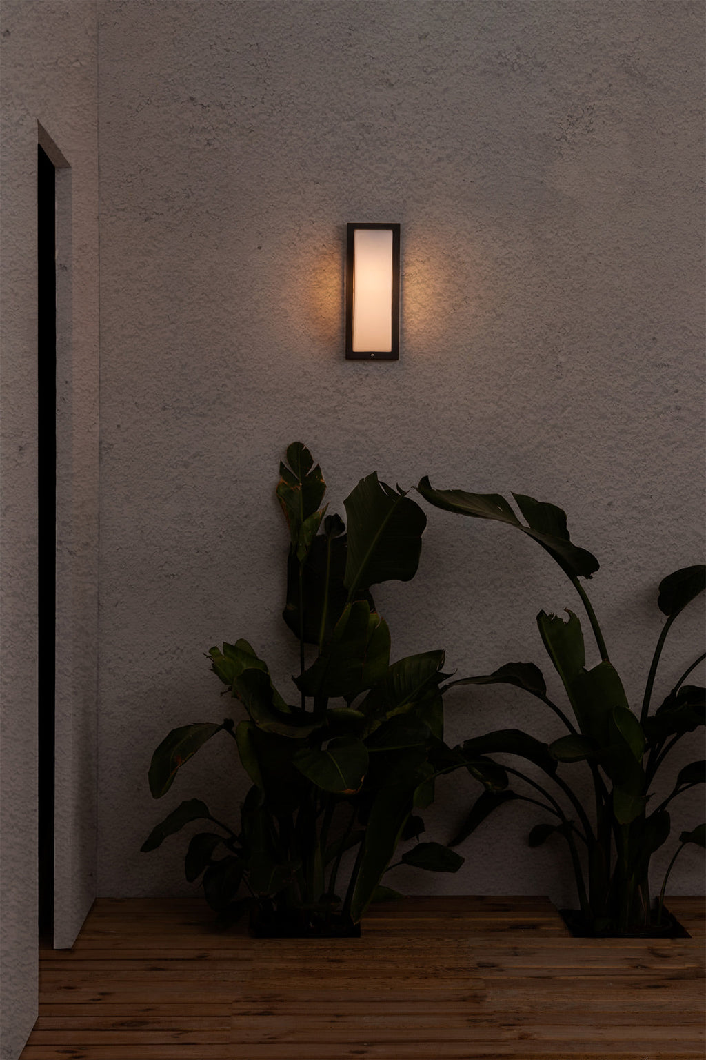 Lámpara de pared exterior MOL gris oscuro FARO 70720 en ambiente, luminaria superficie LED IP44 de aluminio y policarbonato serie 1367 instalada en pared exterior iluminando jardín nocturno