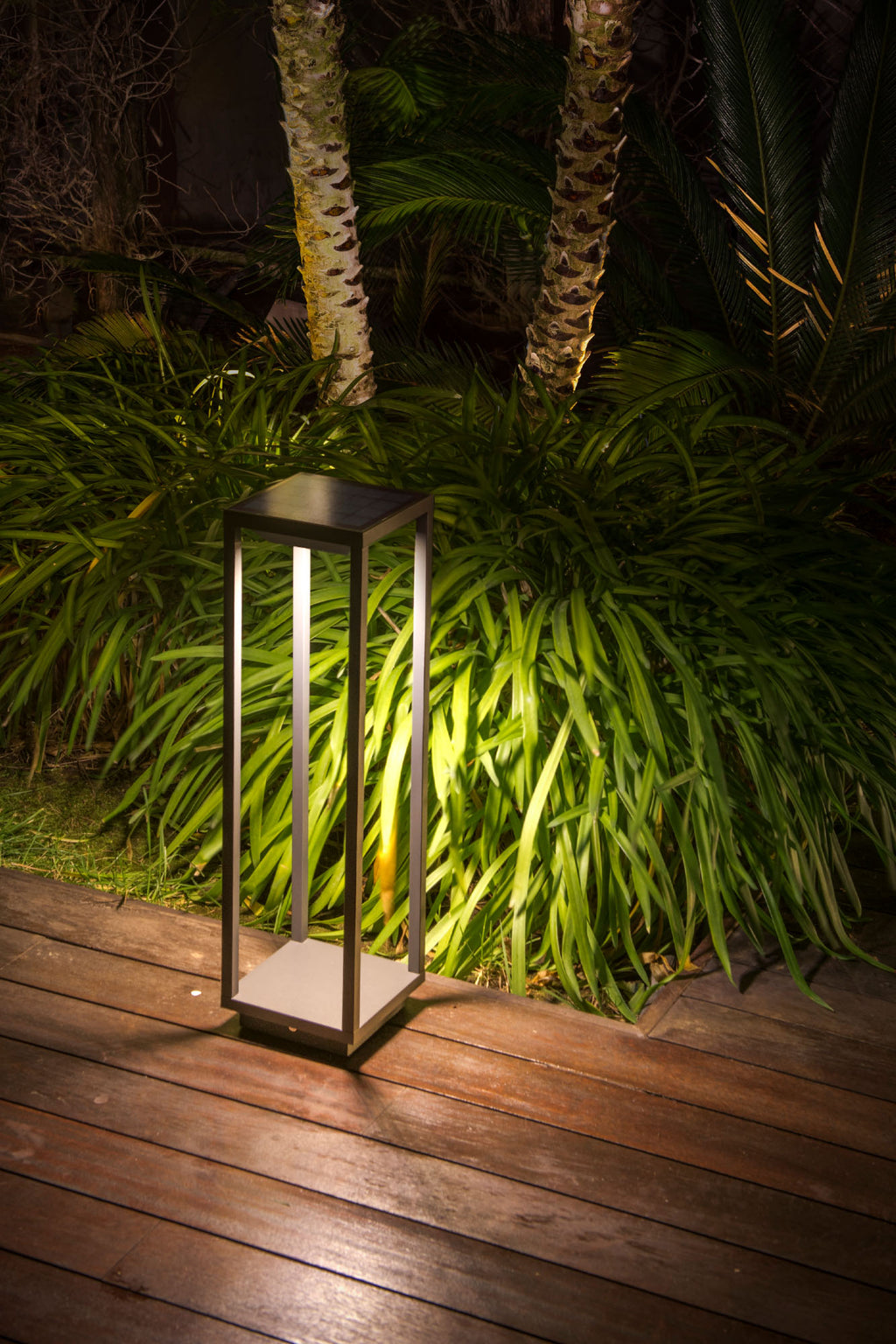 Baliza solar LED SAURA gris oscuro instalada en jardín exterior, faro luminaria superficie con sensor de movimiento activado para iluminación nocturna eficiente y ecológica