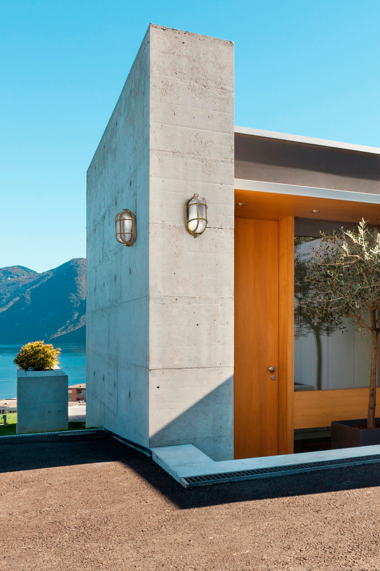 Aplique de pared exterior CABO en latón dorado de FARO modelo 70998, en ambiente de jardín iluminado, lámpara terraza IP44 con cristal opal, iluminación exterior made in Europe