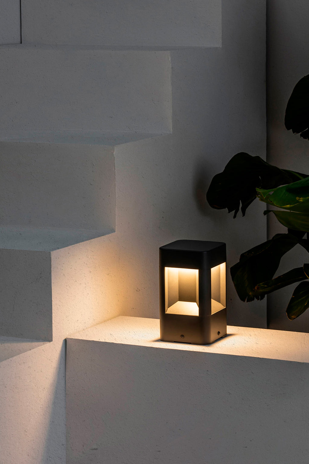 Sobremuro LED NAYA 200 Gris Oscuro FARO 71198 en entorno exterior de jardín, luminaria superficie de aluminio y policarbonato para iluminación LED