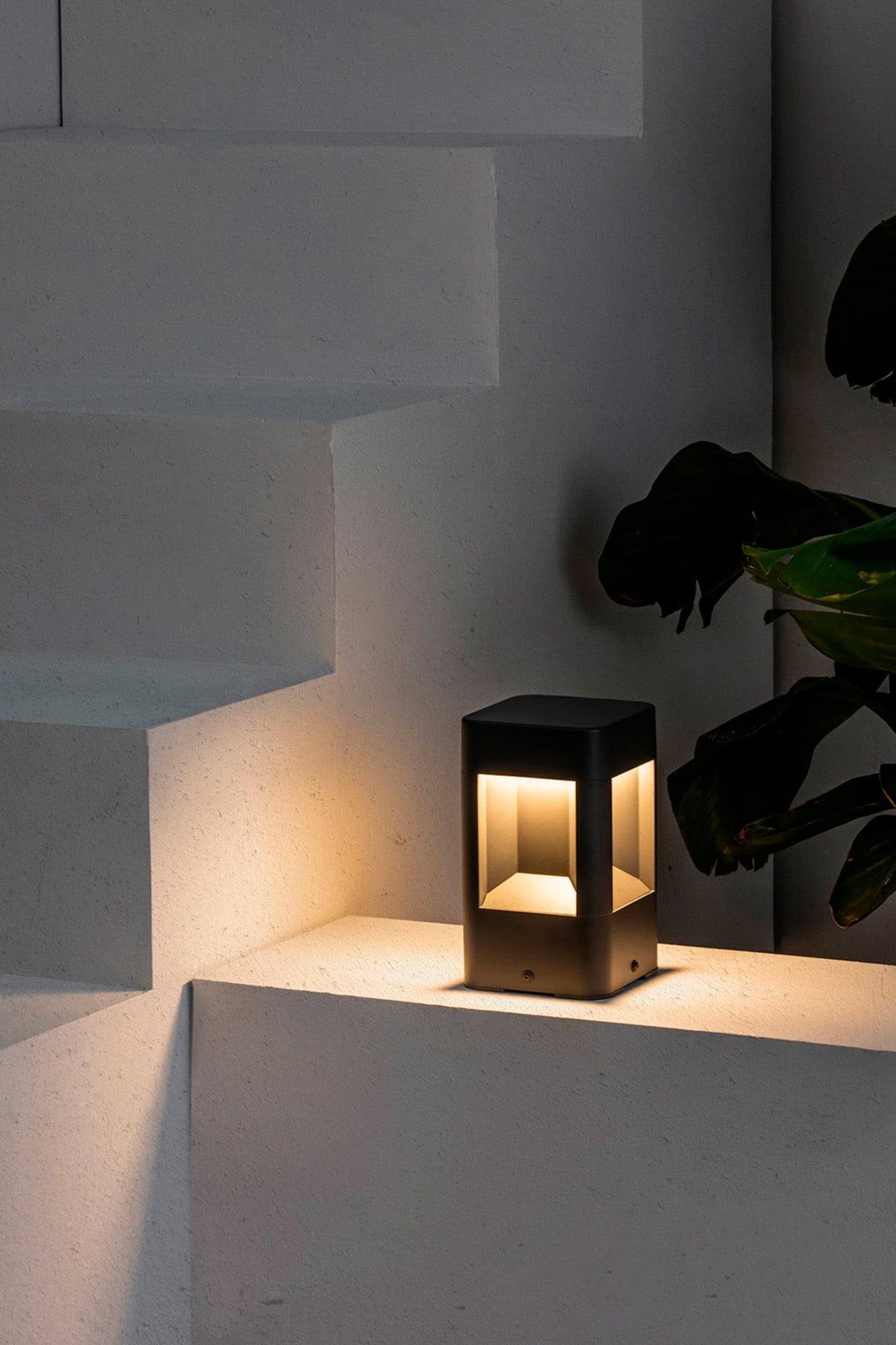 Sobremuro LED NAYA 200 Gris Oscuro FARO 71198 en entorno exterior de jardín, luminaria superficie de aluminio y policarbonato para iluminación LED