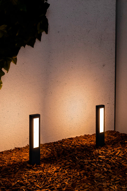 Baliza LED exterior NANDA 500 en gris oscuro instalada en jardín, faro luminaria de suelo serie 71216 de aluminio y policarbonato IP54 para exteriores