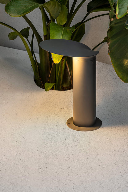 Baliza exterior LOTUS 350 en gris oscuro FARO 71224, luminaria LED de aluminio y policarbonato IP65 con diseño contemporáneo, iluminando jardín moderno en imagen de ambiente.