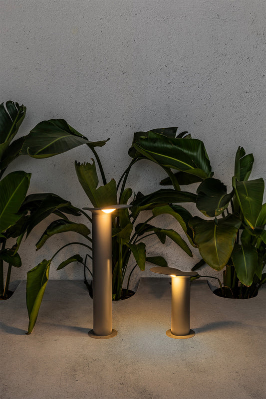 Baliza exterior LOTUS 650 en gris oscuro iluminando jardín moderno, faro de aluminio LED IP65 para iluminación exterior contemporánea, luminaria de superficie colección Lotus.