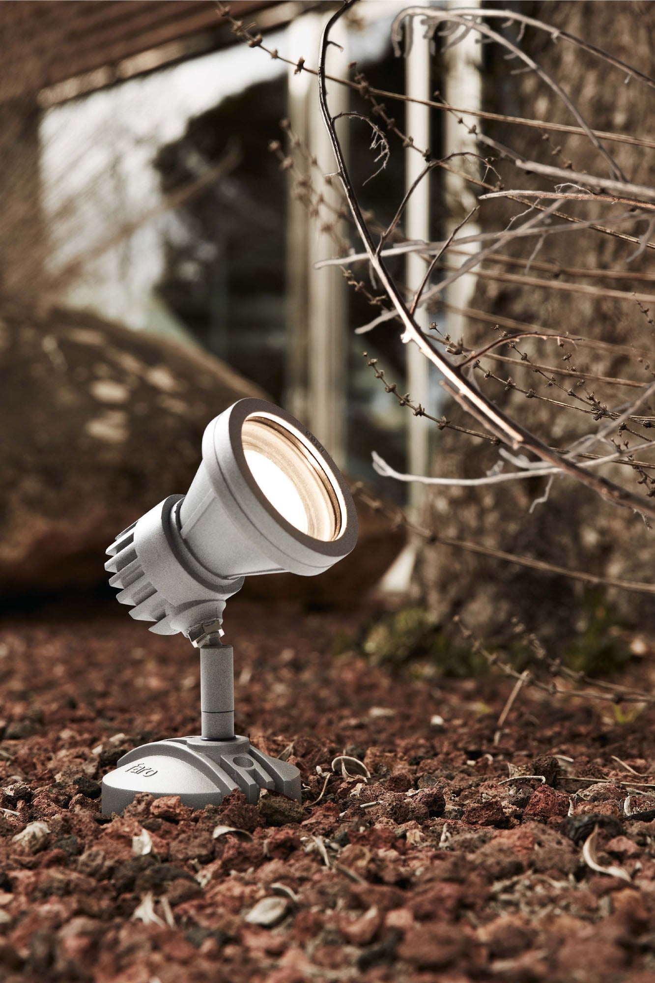 Lámpara proyector exterior PROJECT 73 gris aluminio cristal FARO 71383 colección 1228 instalada en pared de jardín ambiente