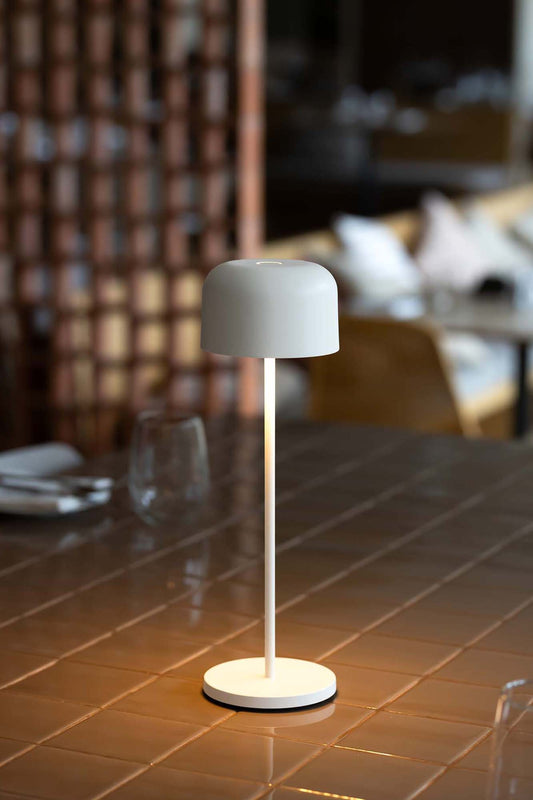 Lámpara portátil MAVIS 200 Blanca de FARO en ambiente de jardín exterior, iluminación LED recargable por USB-C, diseño minimalista para exteriores, modelo 71921