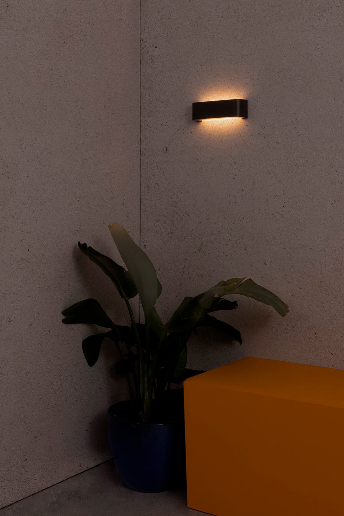 Aplique pared LED exterior Bracket gris oscuro FARO 72272 en ambiente de jardín minimalista, iluminación cálida IP44 en aluminio.