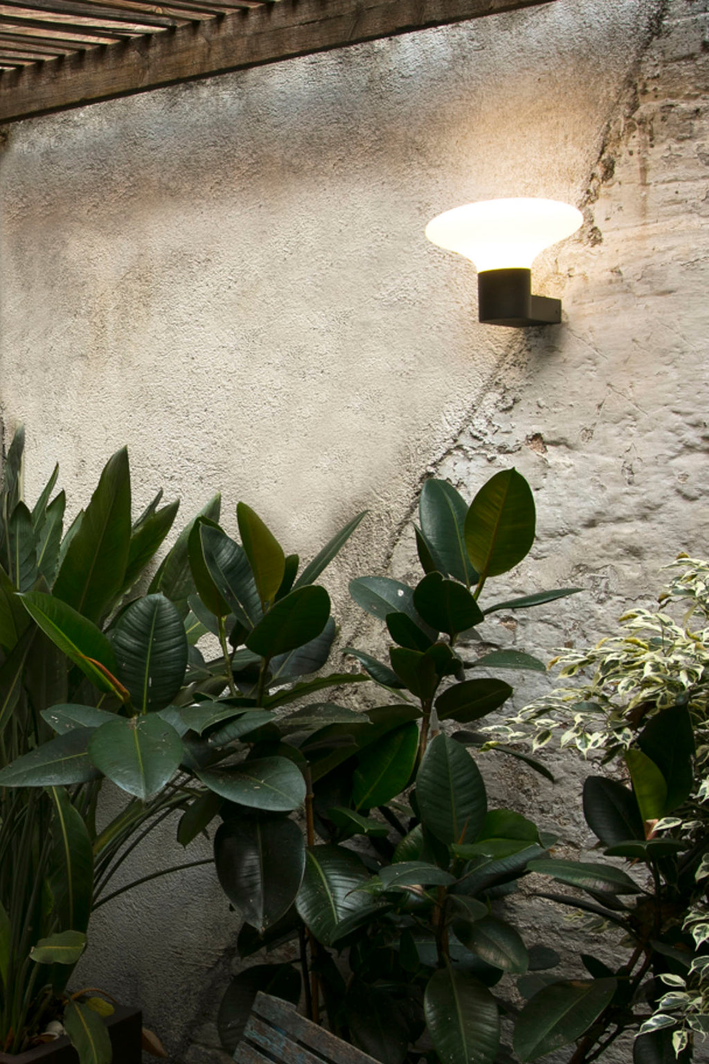 Aplique de pared exterior BLUBS Gris Oscuro FARO 74432A-03 en ambiente de jardín iluminado, luminaria contemporánea de aluminio y PMMA IP44 para exteriores