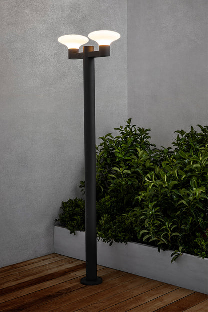 Farola exterior BLUBS 2L en gris oscuro, modelo FARO 74435F2-03, instalada en jardín iluminado, luminaria de superficie en aluminio y PMMA con IP44 para iluminación exterior resistente.