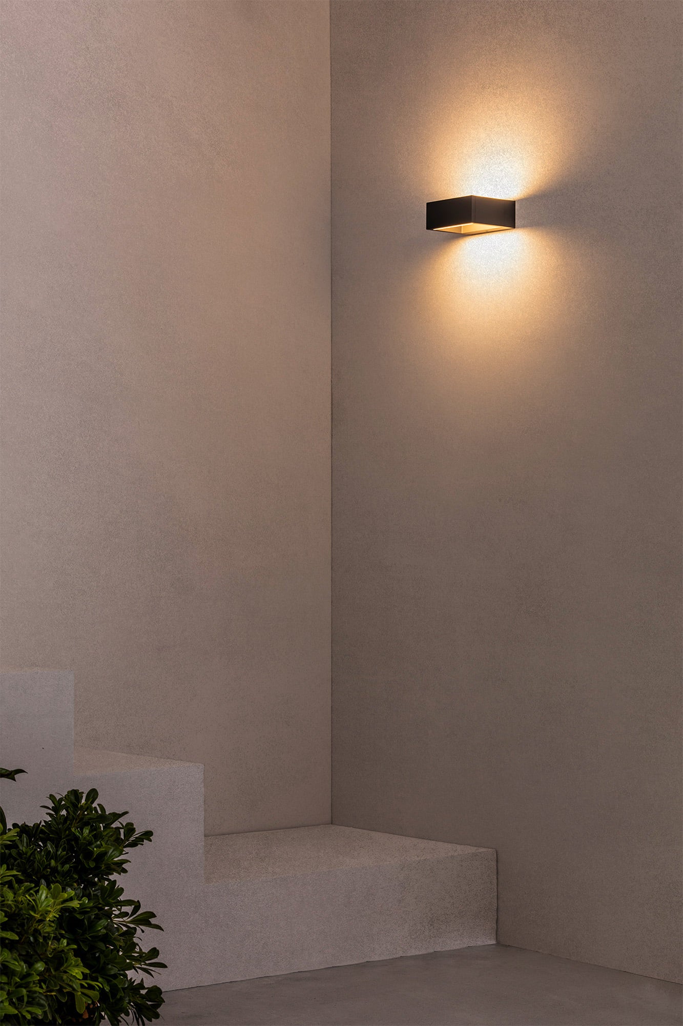 Aplique exterior LED ALP 130 en gris oscuro de FARO (74450) instalado en jardín moderno, luminaria de pared para iluminación exterior y superficie