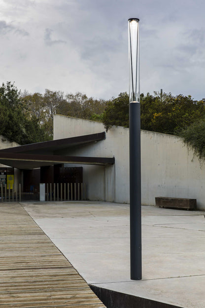 Farola exterior RUSH 3700 en gris oscuro con luz LED 4000K Wide, modelo FARO 750321D, instalada en jardín o parque, luminaria de aluminio y policarbonato IP65 con control DALI, iluminación ambiente para exteriores