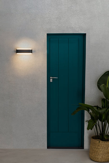 Aplique de pared LED STICKER gris oscuro FARO 75540 en entorno de jardín exterior, iluminación LED IP55 en aluminio y PMMA para exteriores resistentes al agua
