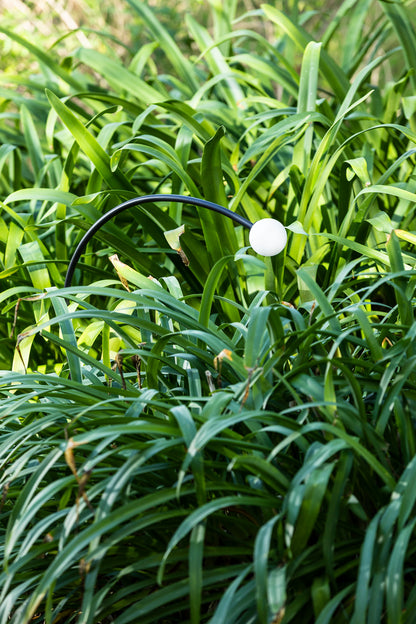 Luminaria estaca CUCA 650 negra 24V faro 75561 en ambiente de jardín exterior, diseño minimalista en acero inoxidable y cristal con protección IP65 para iluminación exterior.