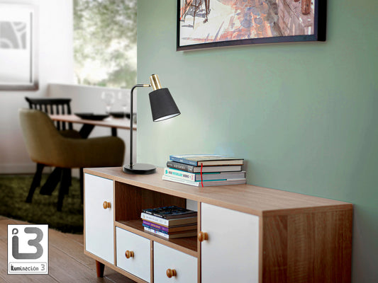 Lámpara de sobremesa Gisela negro y latón de Schuller iluminando un salón o dormitorio moderno y elegante.