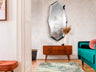 Espejo de pared London de acero pulido Schuller en salón moderno con diseño de cristal, ideal para dormitorio o recibidor.